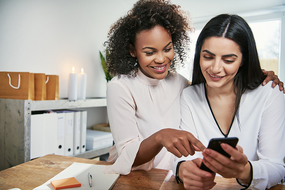 two young businesswomen checking a mobile PMY83QR 4