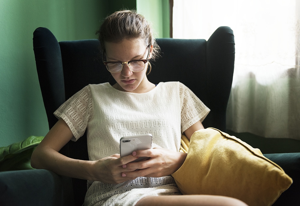 caucasian woman using phone in living room PBJ2WXC 4