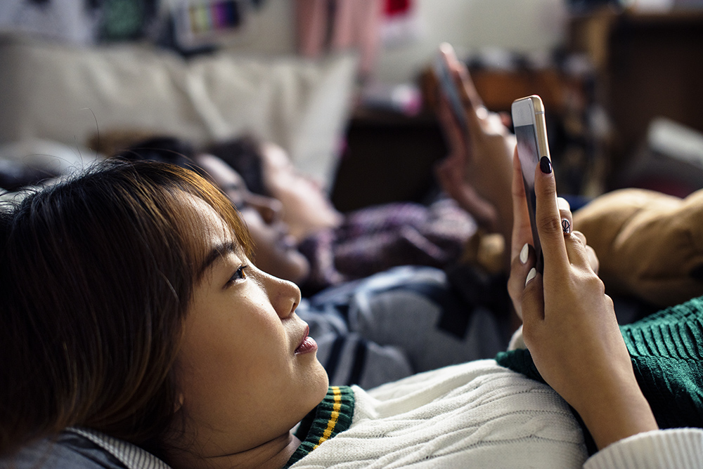 teenage girls using smartphones on a bed internet PDM4F6Z 4